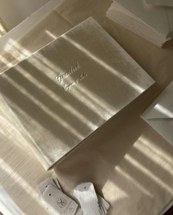 Flat lay of a luxurious wedding guestbook and envelopes in soft natural light.